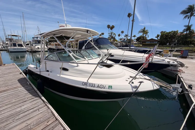 Slide: The Image of 2008 Robalo R225 Walkaround boat docked at marina under clear blue sky. - 2