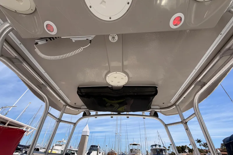 Slide: The Image of 2008 Robalo R225 Walkaround boat interior view with overhead storage and docked boats in background. - 23
