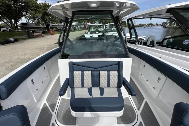 Slide: The Image of 2025 Monterey Elite 30 OB boat interior with blue and white seating, docked by the water. - 16
