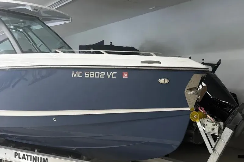 Slide: The Image of 2025 Monterey Elite 30 OB boat on trailer, blue hull with registration number MC 5802 VC. - 2