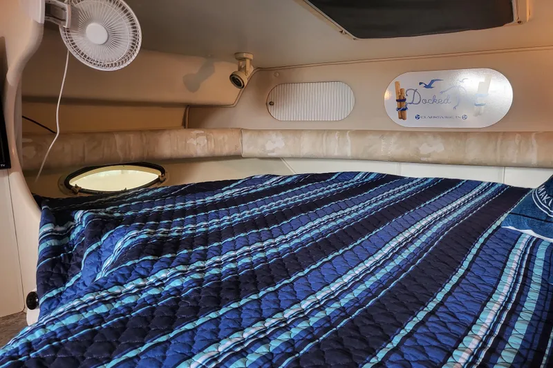 Slide: The Image of Interior cabin of 1999 Rinker Fiesta Vee 330 with blue striped bedding and fan. - 11