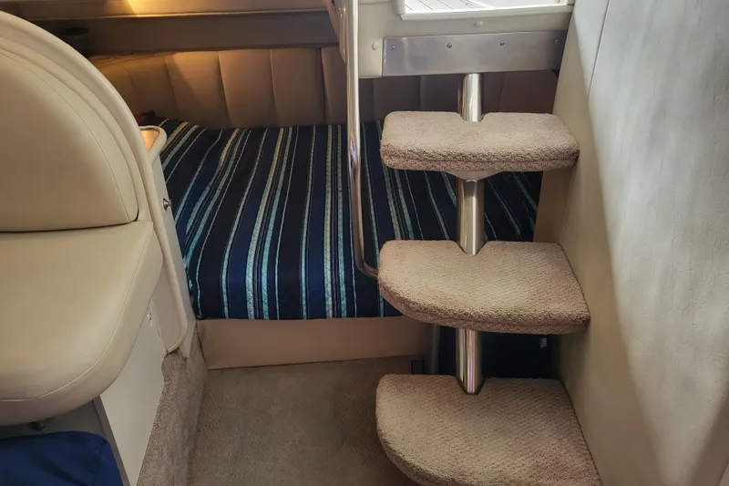 Slide: The Image of Interior of 1999 Rinker Fiesta Vee 330 with striped bedding and carpeted steps. - 13