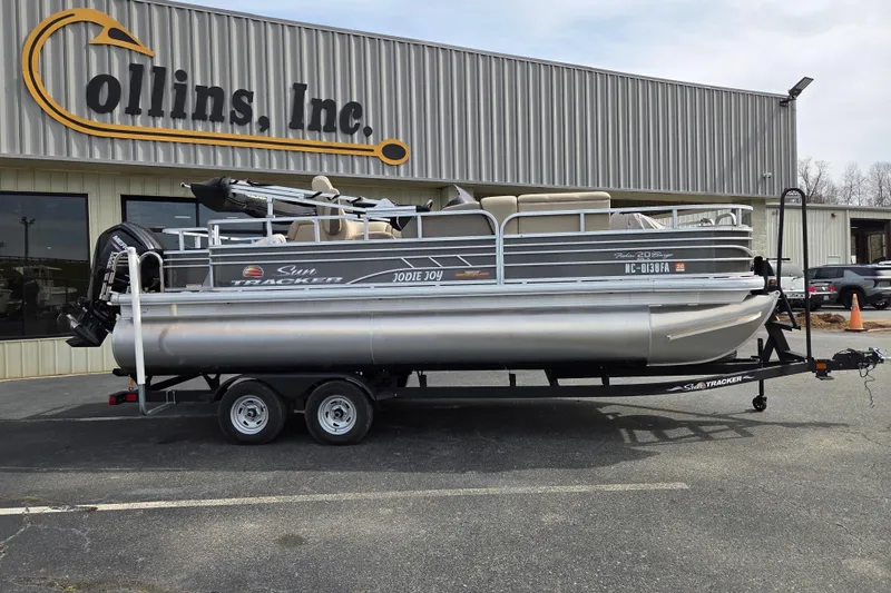 The Image of 2023 Sun Tracker Fishin' Barge 20 DLX pontoon boat on trailer outside dealership. - 0