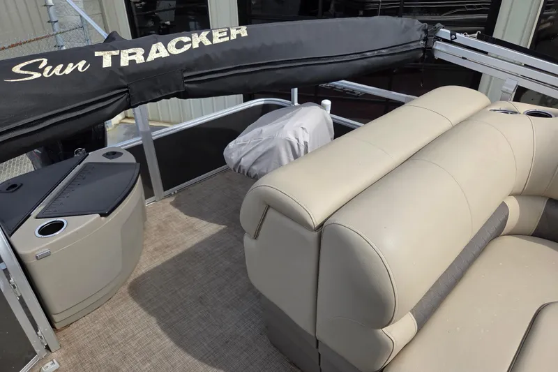 Slide: The Image of 2023 Sun Tracker Fishin' Barge 20 DLX interior with beige seating and storage compartments. - 11