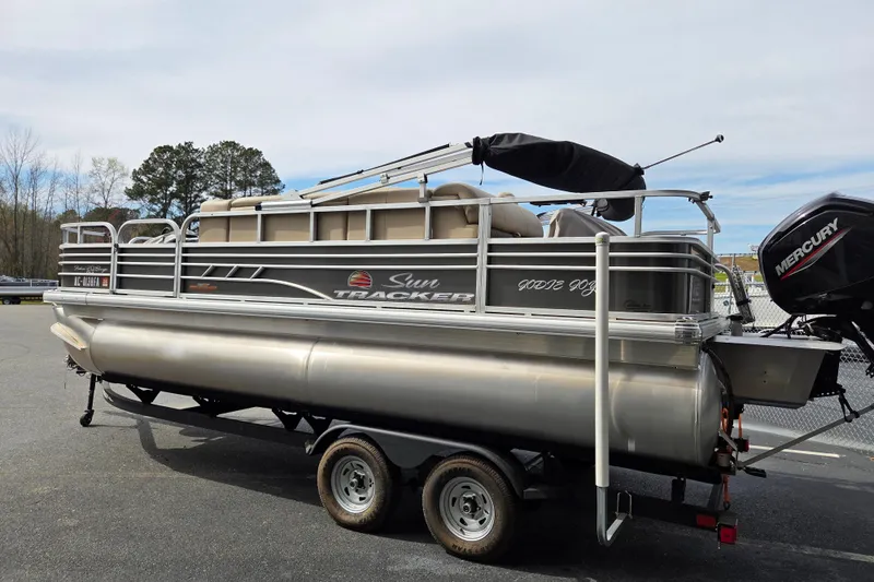 Slide: The Image of 2023 Sun Tracker Fishin' Barge 20 DLX pontoon boat on trailer, parked outdoors. - 4