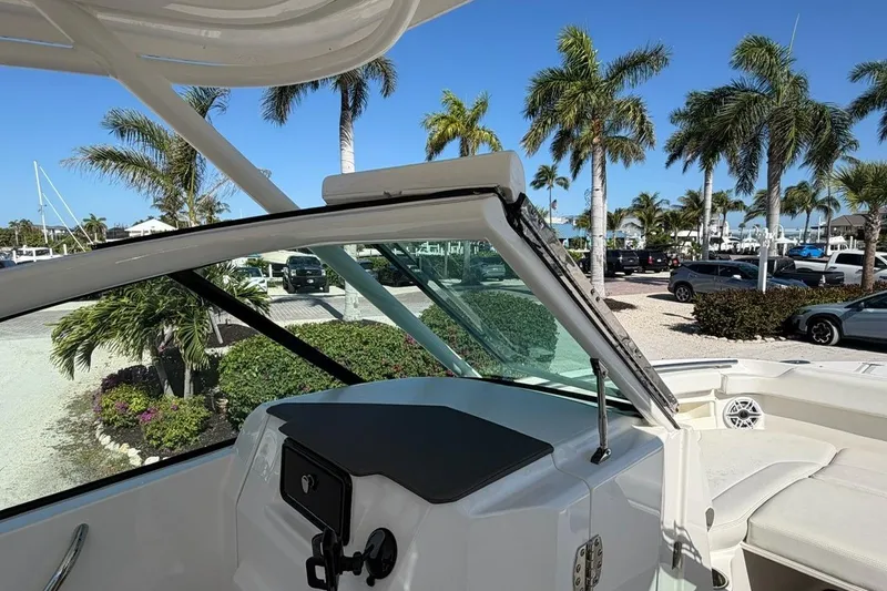 Slide: The Image of 2021 Pursuit DC 266 Dual Console boat interior with palm trees in the background. - 10