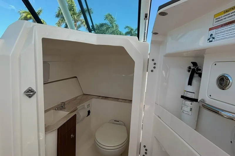 Slide: The Image of 2021 Pursuit DC 266 Dual Console boat interior with toilet and fire extinguisher. - 12