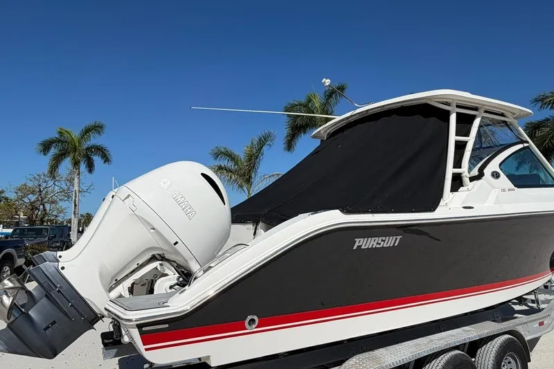 Slide: The Image of 2021 Pursuit DC 266 Dual Console boat with Yamaha engine, parked under clear blue sky. - 3