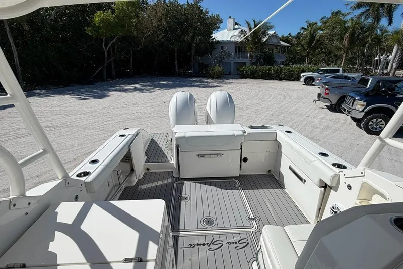 Slide: The Image of 2021 Pursuit DC 266 Dual Console boat interior with seating and storage, parked on sandy lot. - 4