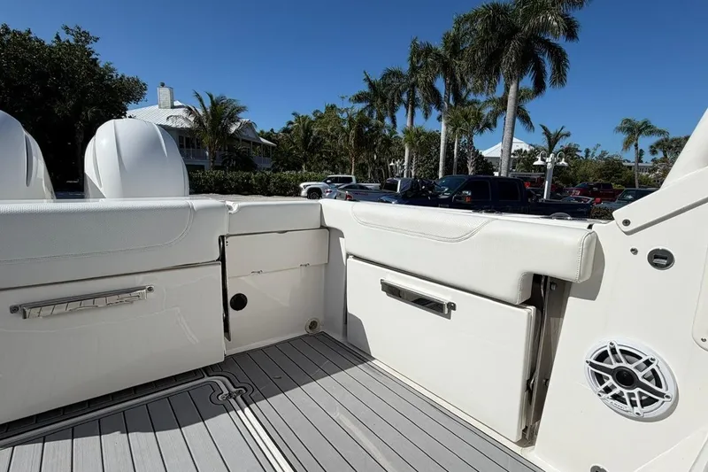 Slide: The Image of 2021 Pursuit DC 266 Dual Console boat interior with seating and speaker, surrounded by palm trees. - 7