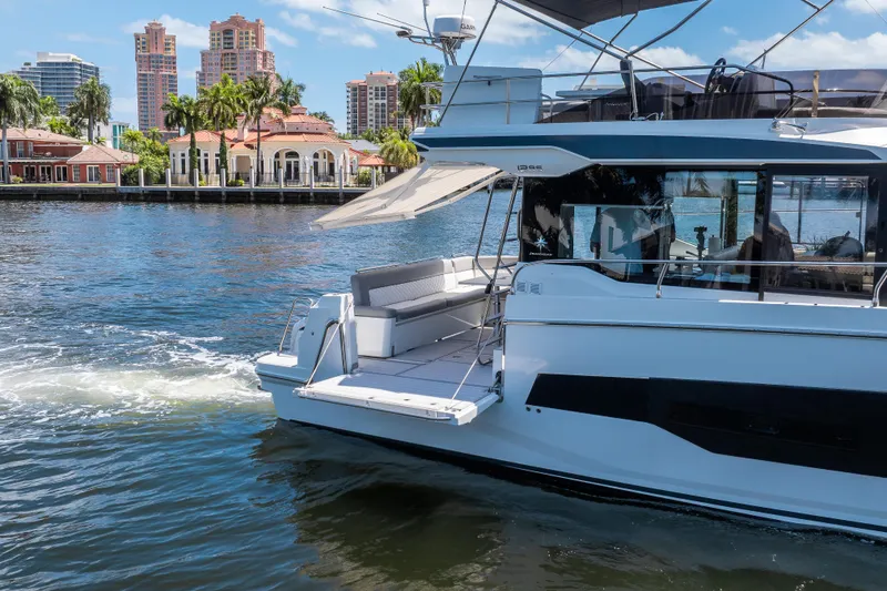 Slide: The Image of 2024 Jeanneau NC 1295 Fly yacht cruising near waterfront homes and palm trees. - 13