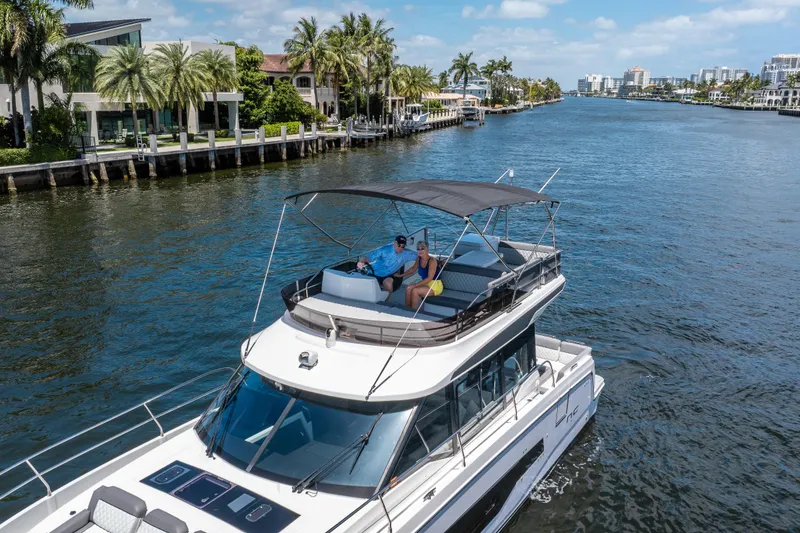 Slide: The Image of 2024 Jeanneau NC 1295 Fly cruising on a scenic waterway with palm trees. - 15