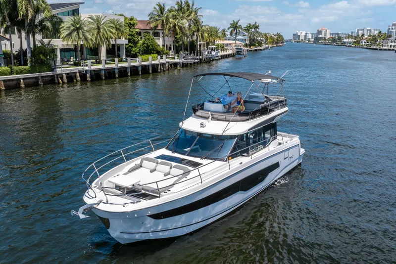 Slide: The Image of 2024 Jeanneau NC 1295 Fly yacht cruising on a scenic waterway with palm trees. - 18