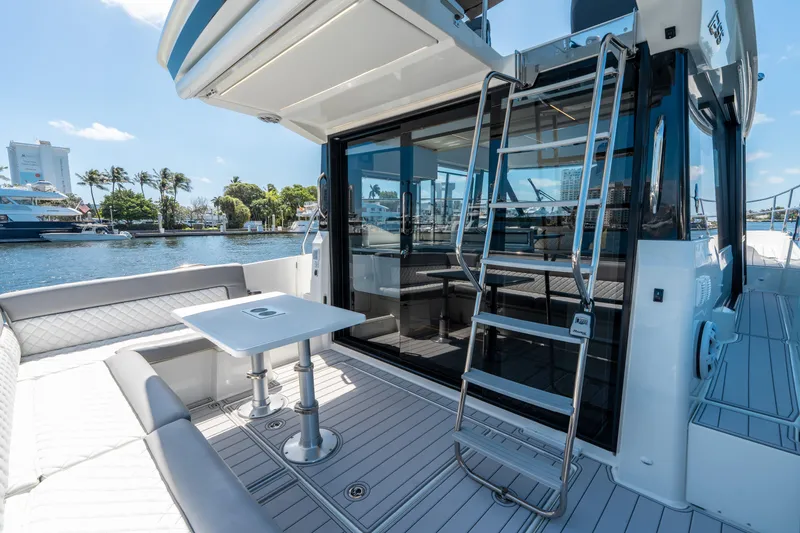 Slide: The Image of 2024 Jeanneau NC 1295 Fly yacht with outdoor seating and ladder, docked by waterfront. - 19