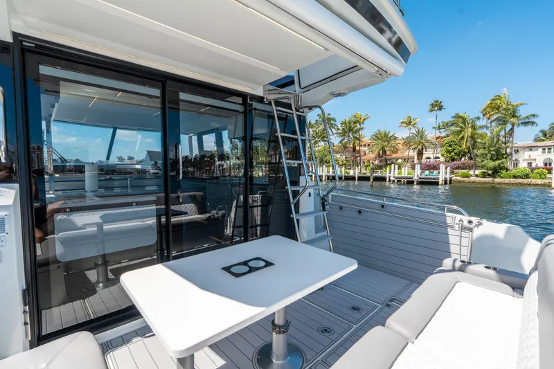 Slide: The Image of 2024 Jeanneau NC 1295 Fly yacht deck with seating, table, and waterfront view. - 23