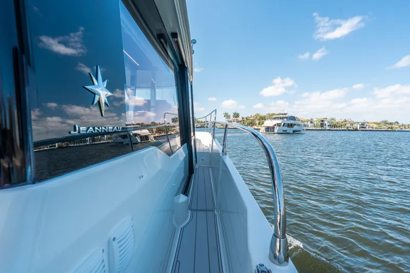 Slide: The Image of 2024 Jeanneau NC 1295 Fly yacht cruising on a sunny day, reflecting water and sky. - 25