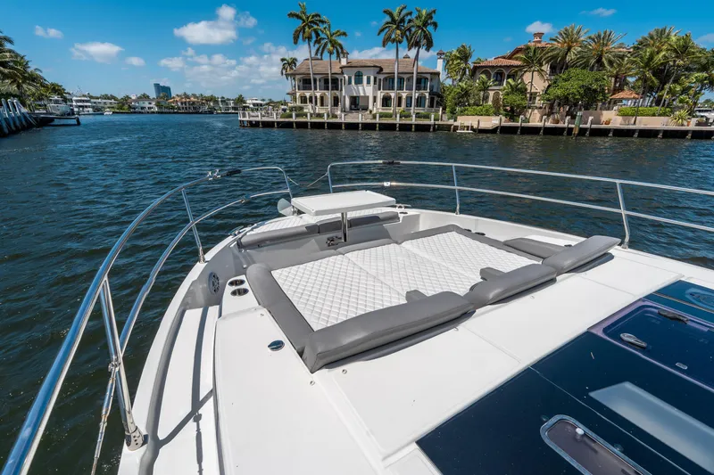 Slide: The Image of 2024 Jeanneau NC 1295 Fly yacht with sunbathing area, cruising near luxury waterfront homes. - 31