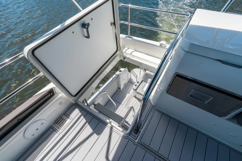 Slide: The Image of 2024 Jeanneau NC 1295 Fly yacht deck with open hatch, overlooking water. - 34