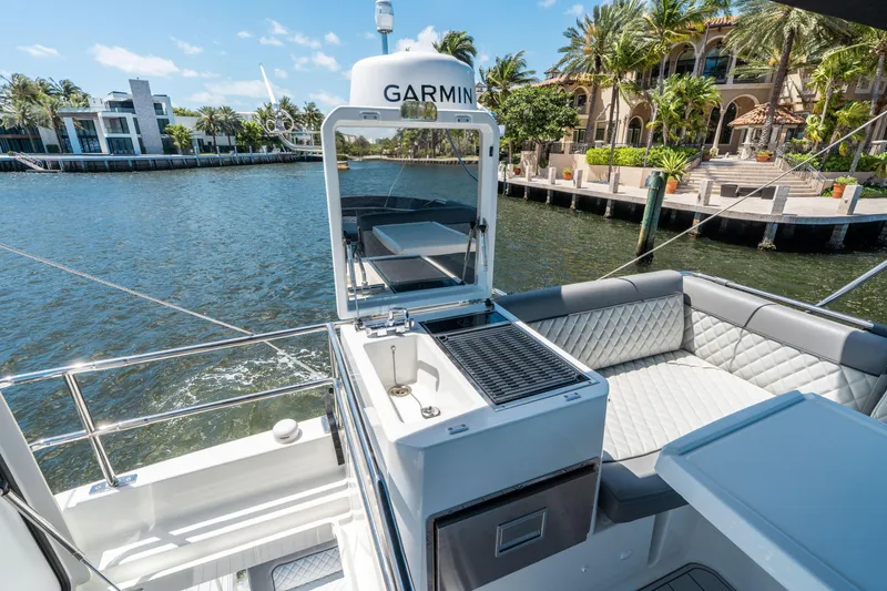 Slide: The Image of 2024 Jeanneau NC 1295 Fly yacht with outdoor seating and grill, docked by luxury waterfront homes. - 35