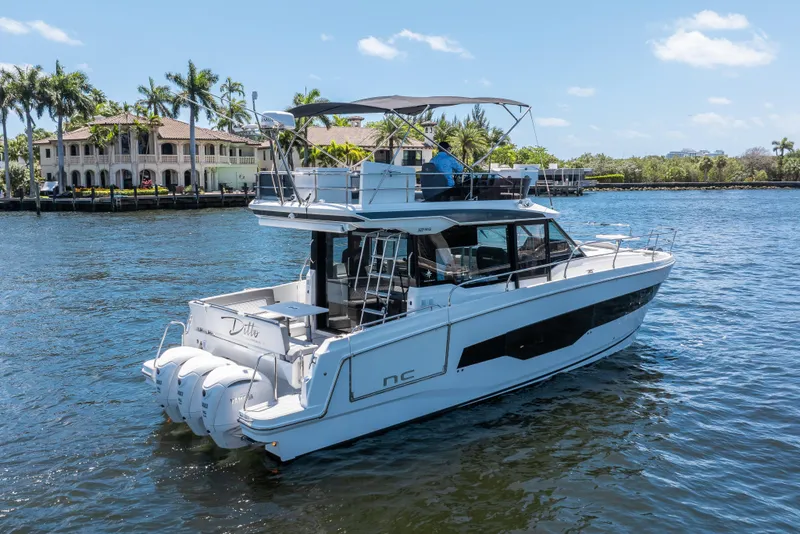Slide: The Image of 2024 Jeanneau NC 1295 Fly yacht cruising on a sunny day near waterfront homes. - 4