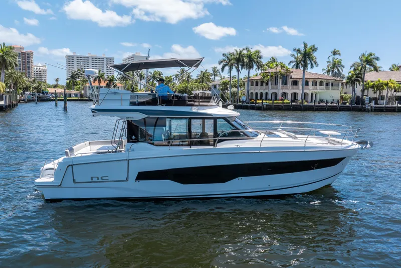 Slide: The Image of 2024 Jeanneau NC 1295 Fly yacht cruising on a sunny waterfront. - 5