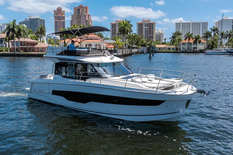 Slide: The Image of 2024 Jeanneau NC 1295 Fly yacht cruising in a scenic waterfront setting. - 6