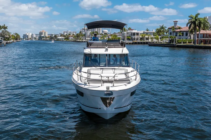 Slide: The Image of 2024 Jeanneau NC 1295 Fly yacht cruising on a scenic waterway with cityscape backdrop. - 7