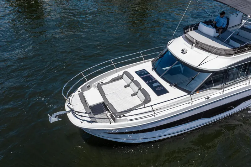 Slide: The Image of 2024 Jeanneau NC 1295 Fly yacht cruising on water, featuring spacious deck and modern design. - 9