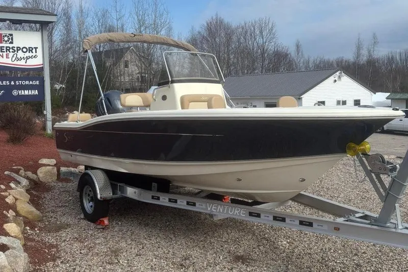 The Image of 2025 Scout 195 Sportfish boat on trailer at Danversport Marine under clear blue sky. - 0