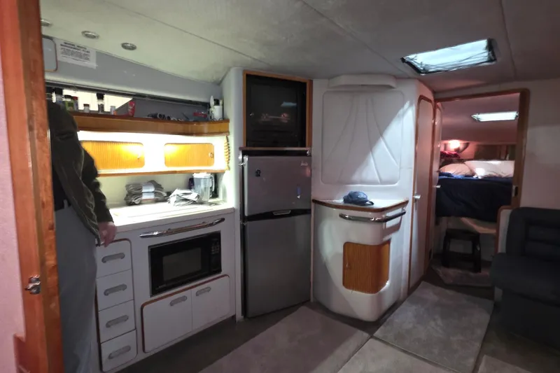 Slide: The Image of Interior of 1989 Sea Ray 420 Sundancer yacht with kitchenette and cozy sleeping area. - 28