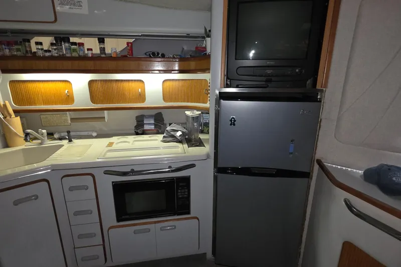 Slide: The Image of 1989 Sea Ray 420 Sundancer kitchen with microwave, fridge, and TV. - 31