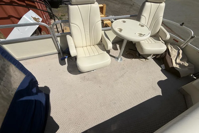 Slide: The Image of 2005 Bennington 2575RL boat interior with white seats and a small round table. - 19