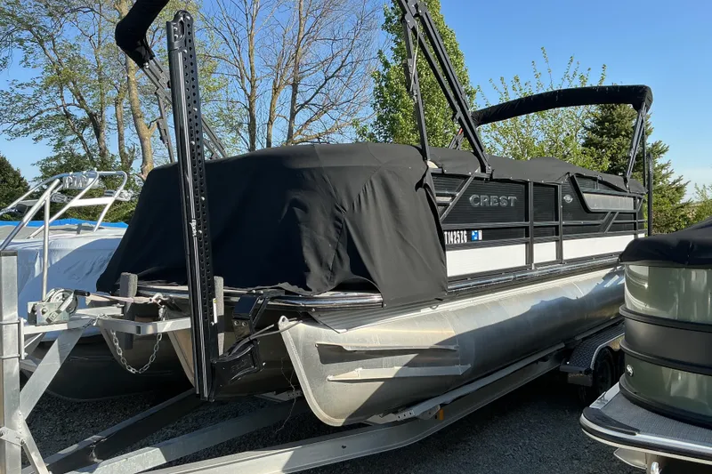 The Image of 2019 Crest Classic 230 SLC pontoon boat covered, parked on trailer. - 1