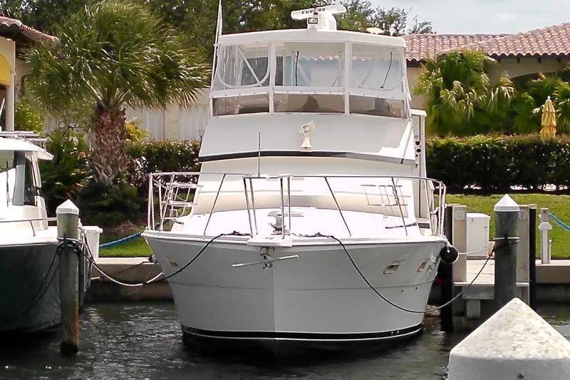 The Image of 1986 Viking 44 Motor Yacht docked at a marina, surrounded by lush greenery. - 0