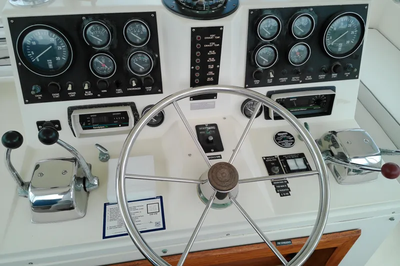 Slide: The Image of 1986 Viking 44 Motor Yacht helm with gauges, steering wheel, and throttle controls. - 13