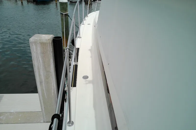 Slide: The Image of 1986 Viking 44 Motor Yacht docked, showing side deck and railing near water. - 23