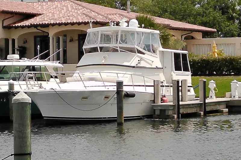 Slide: The Image of 1986 Viking 44 Motor Yacht docked near a waterfront home. - 65