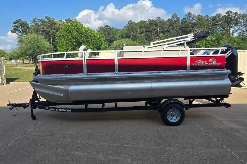 Slide: The Image of 2026 Sun Tracker Bass Buggy 18 DLX pontoon boat on trailer, parked outdoors. - 11