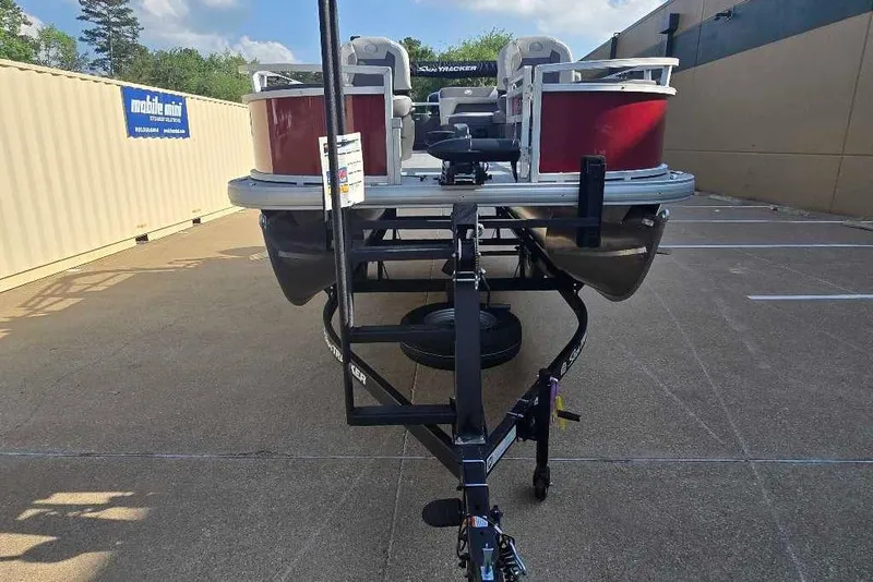 Slide: The Image of 2026 Sun Tracker Bass Buggy 18 DLX pontoon boat on trailer in parking lot. - 2