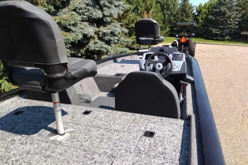 Slide: The Image of 2026 Tracker Pro Team 190 boat interior with steering wheel and seating, parked outdoors. - 2