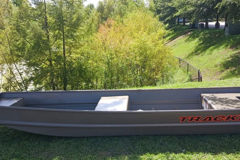The Image of 2026 Tracker Grizzly 14 Jon boat on grassy area near trees and water. - 0