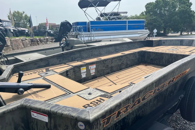 Slide: The Image of 2026 Tracker Grizzly 1756 T Marsh boat with camouflage design, parked outdoors. - 5