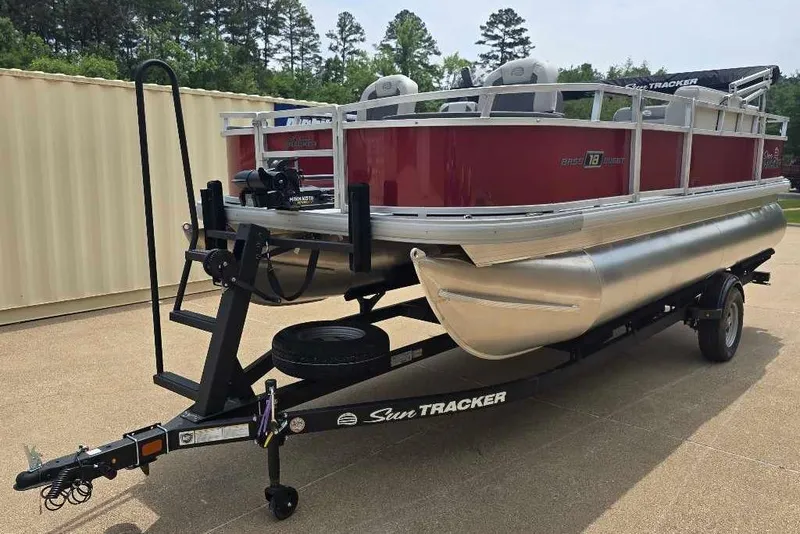 The Image of 2026 Sun Tracker Bass Buggy 18 DLX pontoon boat on trailer, parked outdoors. - 0