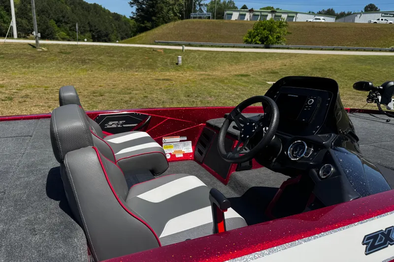 Slide: The Image of 2019 Skeeter ZX200 boat interior with steering wheel and seats, parked on grassy area. - 12