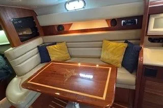Slide: The Image of 2002 Pursuit 3800 Express yacht interior with cushioned seating and wooden table. - 10