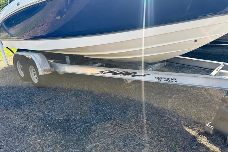 Slide: The Image of 2005 Chaparral 236 SSi boat on a dual-axle trailer, parked on gravel. - 5