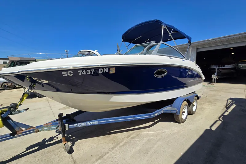 The Image of 2010 Chaparral Sunesta 224 boat on trailer, blue and white exterior, sunny day. - 0