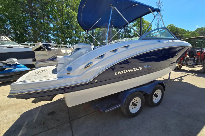 Slide: The Image of 2010 Chaparral Sunesta 224 boat on trailer, blue and white design, parked outdoors. - 2
