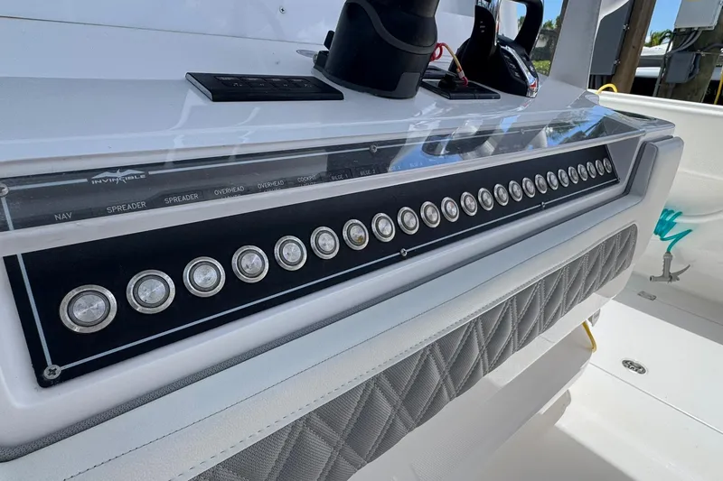 Slide: The Image of Control panel of 2024 Invincible 35 Catamaran with multiple switches and padded detailing. - 3