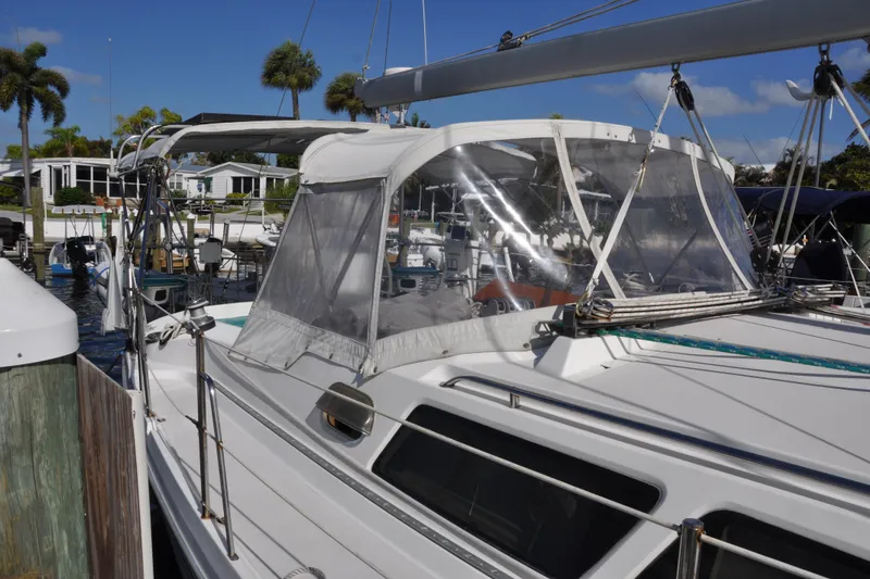 Slide: The Image of 2003 Catalina 387 sailboat docked, featuring a clear cockpit enclosure and tropical surroundings. - 10